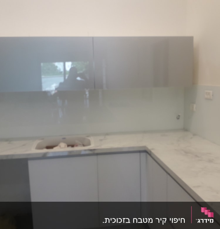 זכוכית שקופה על קיר מטבח מעל השיש